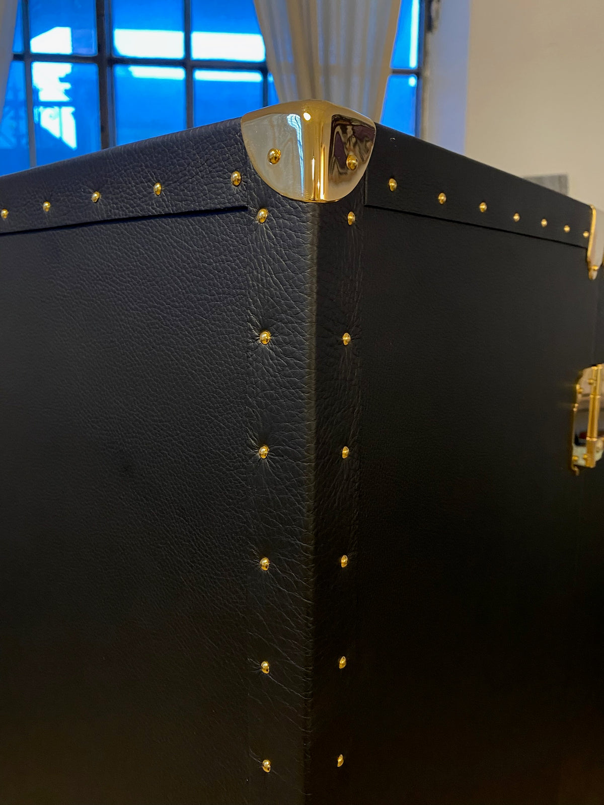 Dettaglio di un angolare in ottone e delle borchie su un baule in vera pelle nera, Piatti Milano